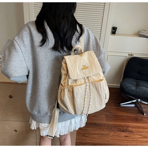 Detailed view of cream-colored backpack featuring YOU BEAR embroidery and drawstring closure