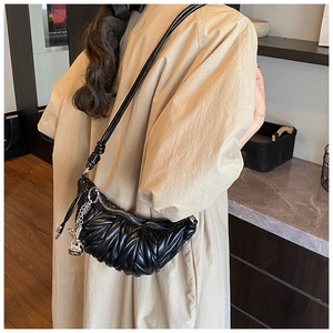Détail du sac croissant noir plissé avec chaîne argentée et pendentif ours mignon
