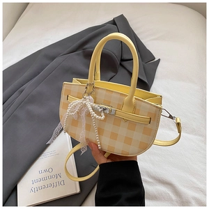 Detail of yellow plaid bucket bag with pearl bow pendant and silver twist lock