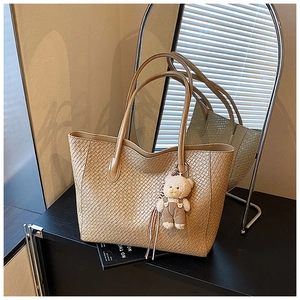 Detail view of apricot woven tote bag featuring a cute bear plush keychain accessory