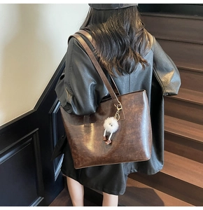 Detail of dark brown tote bag with retro leather texture and plush charm on shoulder