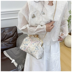 Detail of floral embroidery and pearl handle on a vintage style crossbody bag