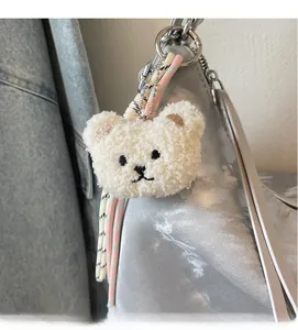 Dettaglio di un grazioso ciondolo a orsetto di peluche con corda intrecciata su una borsa
