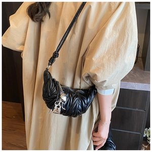 Gros plan du sac demi-lune noir matelassé avec pendentif cœur porté par un mannequin