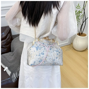 Detail of vintage floral embroidery with pearl accents on a classic clasp handbag