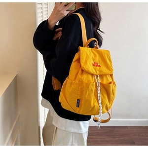 Side view of vibrant yellow waterproof nylon backpack featuring red You BEAR embroidery