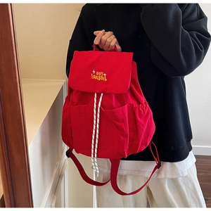 Detail of red backpack featuring yellow letter embroidery and convenient side pocket