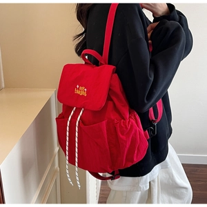Detail view of red nylon backpack with yellow letter embroidery and drawstring closure