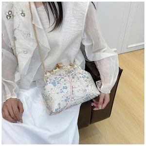 Detail of vintage floral embroidery crossbody bag with pearl accents and gold chain strap