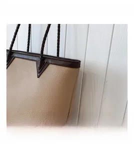Close-up of litchi grain texture and contrast stitching on a beige tote bag