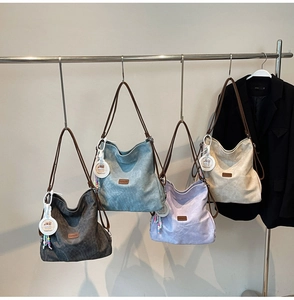 Close-up of high-capacity tote bags in gray, blue, purple, and beige hanging in a row
