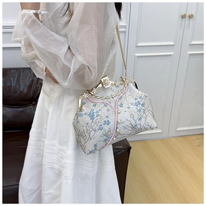 Detailed macro view of the vintage floral jacquard fabric and pearl accents on the handbag