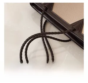 Detail showing the woven texture of the dual-color tote bag handle on marble surface