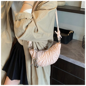 Détail du sac croissant matelassé rose avec bandoulière nouée et chaîne à motif cœur