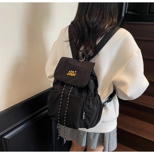Rear view of model wearing a black nylon backpack with yellow embroidery on stairs