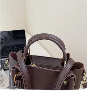 Close-up of the reinforced handle and premium gold hardware on the brown leather tote