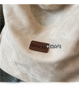Close-up of the beige canvas texture and embossed brown leather label on the backpack
