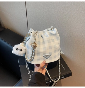 Detail der blau-weiß karierten Beuteltasche mit Kettenriemen und Plüschbär-Anhänger