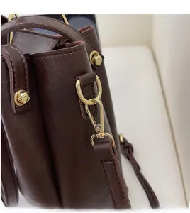 Detailed close-up of durable gold metal hooks and leather texture on a bucket bag