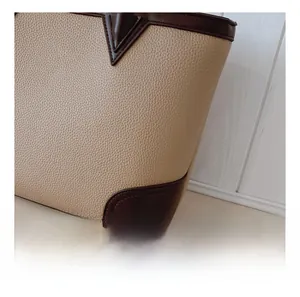 Detailed macro shot of lychee grain leather stitching and reinforced corners on a tote bag