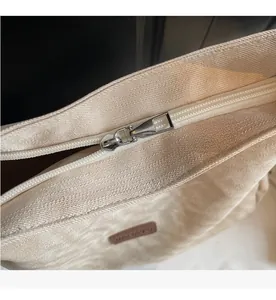 Close-up of smooth metal zipper closure and canvas texture on the beige tote bag