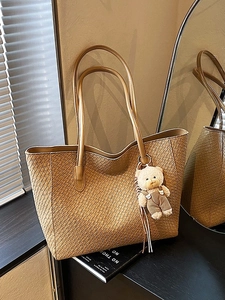 Minimalist camel woven tote bag for women with a cute plush bear charm in cozy indoor setting