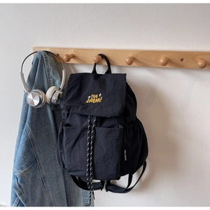 Detail of black nylon backpack featuring yellow embroidery and drawstring closure