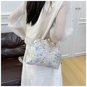 Detailed view of gray fabric crossbody bag with blue floral embroidery and pearl accents
