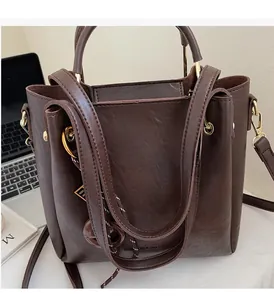 Detail of dark brown bucket bag featuring double handles and adjustable long shoulder strap