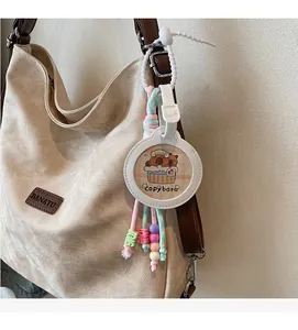 Detail of Capybara charm with macaron tassels and beads on a beige canvas tote bag