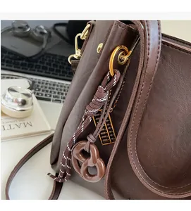 Detailed close-up of brown leather bag with pretzel charm and golden abacus ornament