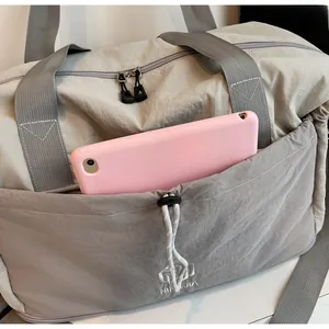 Close-up of grey travel bag featuring a functional front drawstring pocket for tablet storage