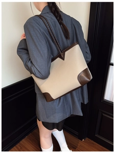 Detailed view of beige tote bag with brown leather patches and braided shoulder strap