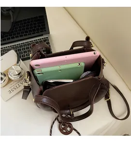 Interior view of large dark brown leather crossbody bag holding tablets and phone
