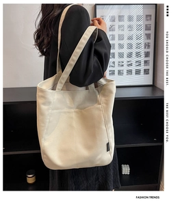 Close-up of a large beige canvas tote bag showing vertical stitching and strap details