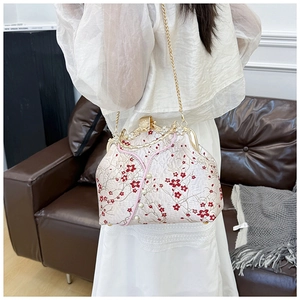 Detailed view of embroidery plum blossom pattern on vintage crossbody bag with gold chain