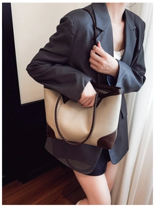 Detail view of large color-block tote bag with woven handles on professional model