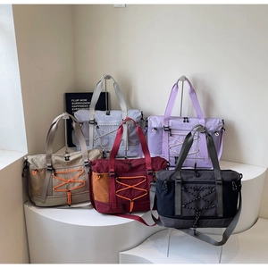 Détail de grands sacs de voyage en cinq couleurs avec cordon élastique sur socles blancs