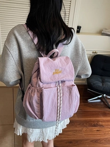Light purple nylon backpack with drawstring flap and embroidery shown on a model