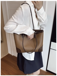 Detail of large tote bag showing brown lychee leather and woven shoulder strap