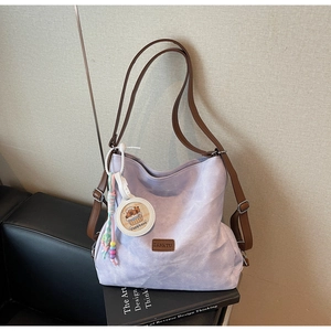 Detail of lavender canvas tote with brown straps and cute capybara charm on side