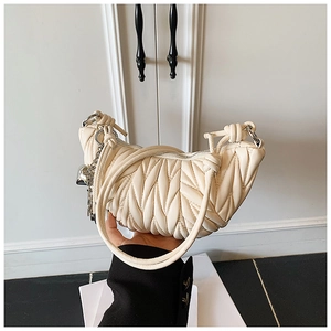 Détail du sac demi-lune matelassé crème avec poignée nouée et fermeture éclair argentée