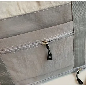 Close-up of smooth metal zipper and textured nylon fabric on the gray travel bag
