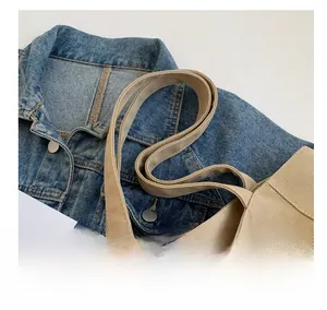 Detail view of wide canvas handles and thick woven texture on a khaki tote bag
