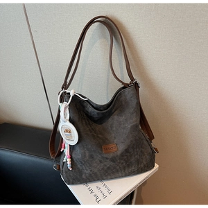 Detailed macro view of dark gray frosted tote bag with retro leather straps and side pendant