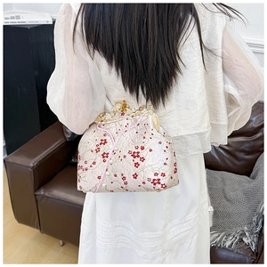 Close-up of red flower embroidery and rhinestone pearl buckle on vintage beige bag