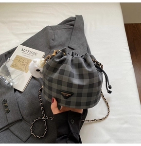 Detail der grau karierten Beuteltasche mit Kordelzug, Goldkette und Plüsch-Anhänger
