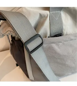Detail of adjustable smooth shoulder strap on light gray travel bag with black buckle