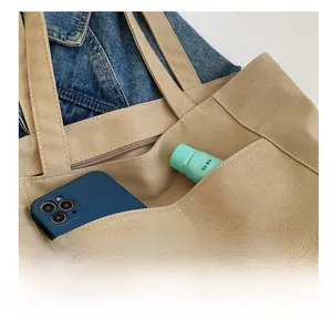 Detail of internal slip pocket on a beige canvas tote bag showing stitching and storage