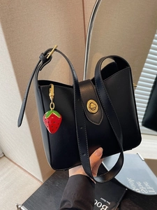 Bolso cubo retro de cuero negro mate con cierre dorado y colgante de fresa